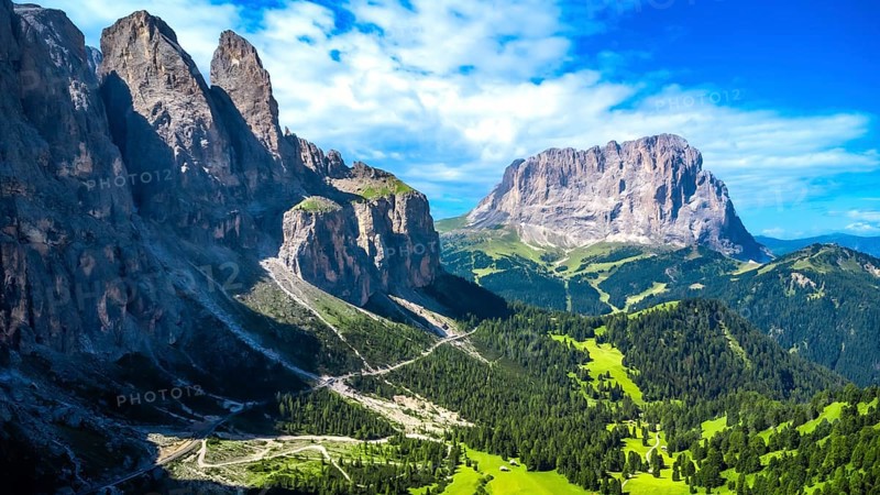 Breathtaking summer landscape in the dolomites, featuring a winding road through lush green valleys and towering peaks