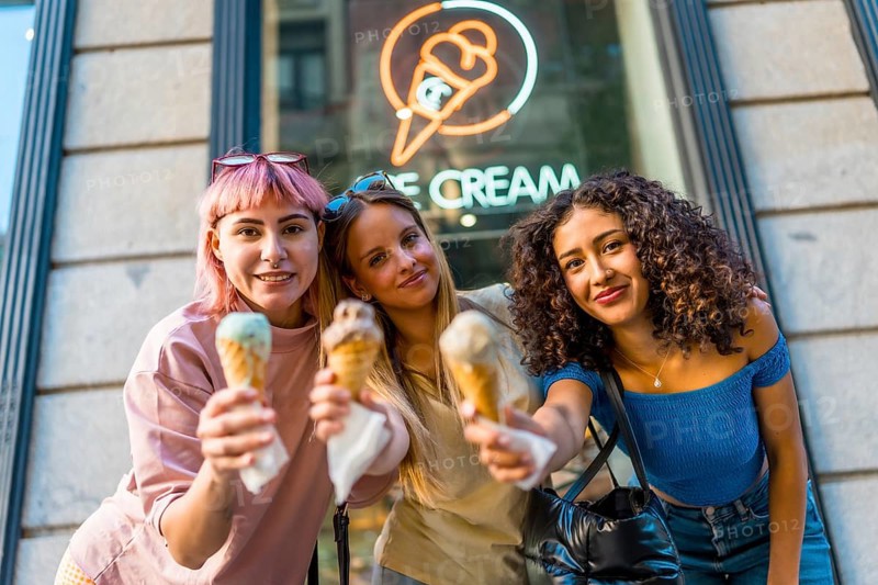 Three beauty different woman holding delicious ice creams outside the store