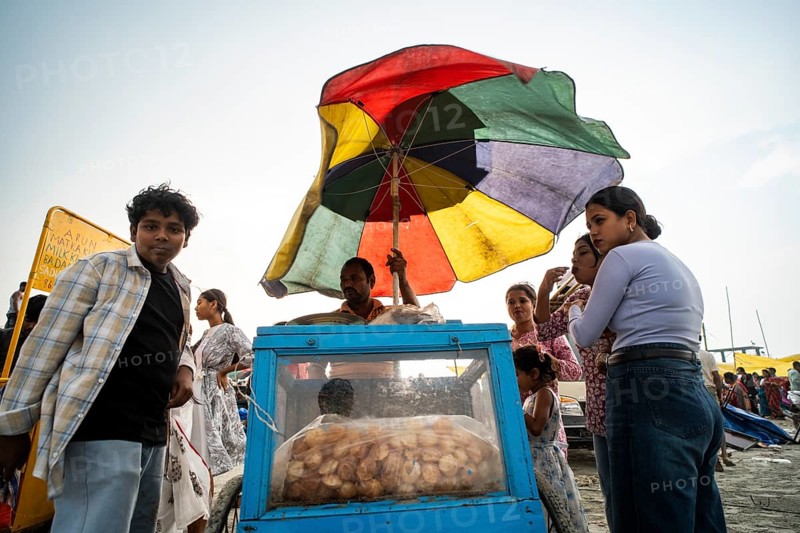 GUWAHATI, INDIA - APRIL 5: A vendor sells panipuri as he stand under a large umbrella during a pre monsoon storm in Guwahati, India on April 5, 2025