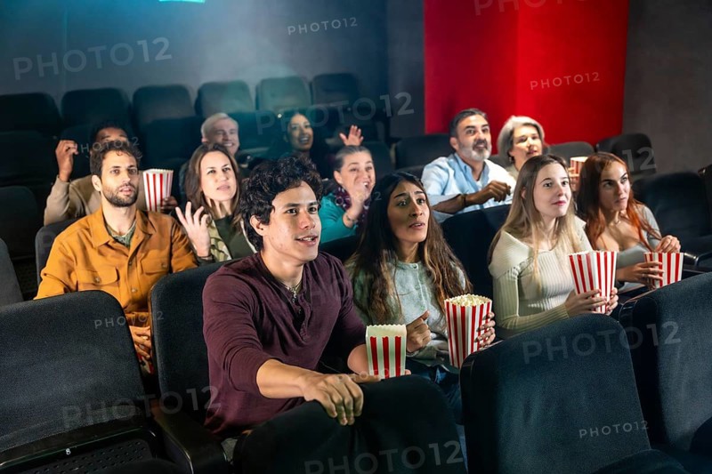 People are watching a movie and eating popcorn in a movie theater, enjoying the show together