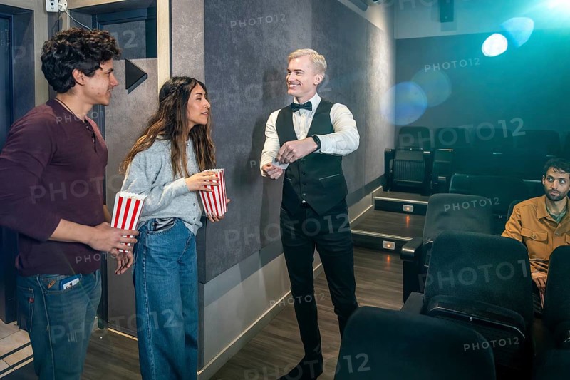 Couple holding popcorn buckets giving their tickets to the usher before entering the movie theater