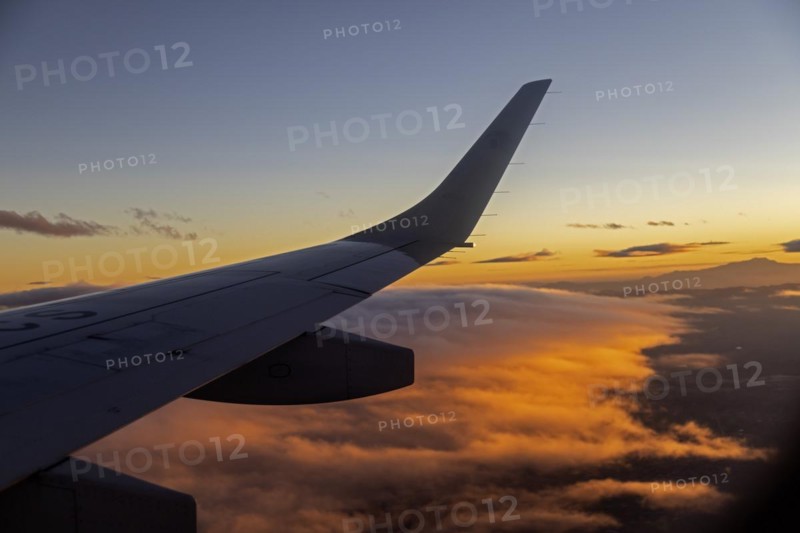 Mexico City, An AeroMexico Connect Embraer jet flies over orange clouds as it approaches Mexico City