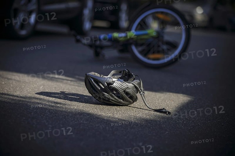 Symbol photo on the subject of bicycle accidents (posed scene) . A broken bicycle helmet lies next to a bicycle on a road Berlin, 21/08/2024