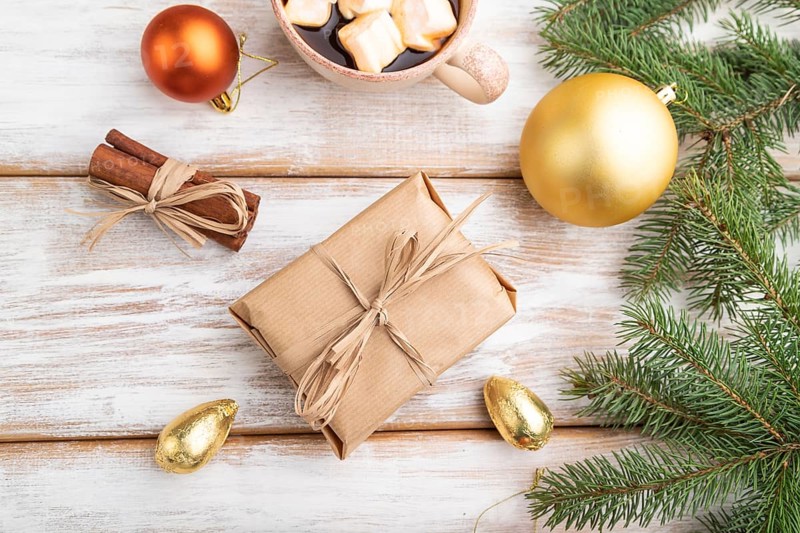 Christmas or New Year composition. Decorations, box, golden balls, cinnamon, fir and spruce branches, cup of coffee, on a white wooden background. Top view, close up, flat lay