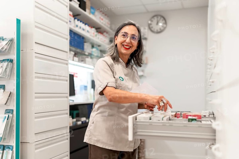 Side view photo of a woman cheerful pharmacist smiling while working in the storage room