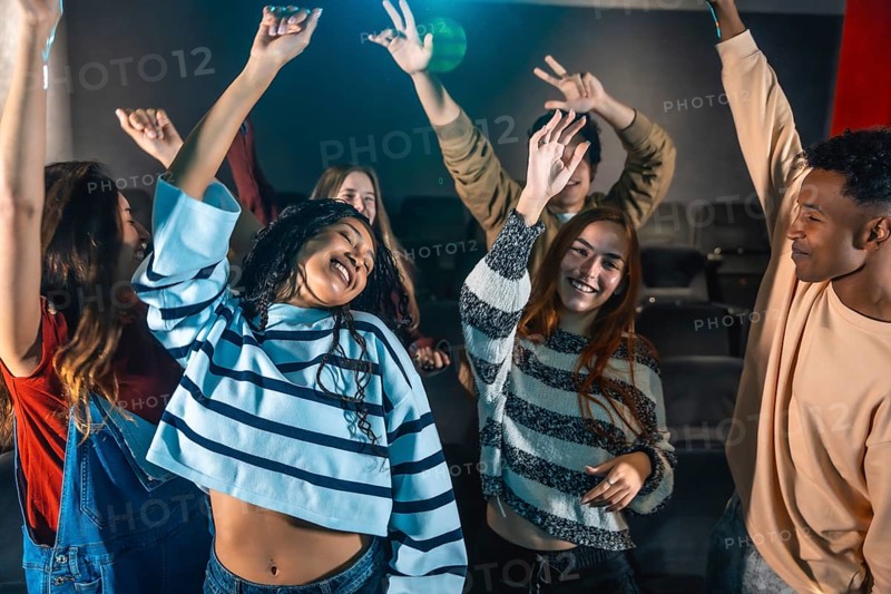 Friends are dancing and having fun at a movie disco event inside a cinema, enjoying music and the company of each other
