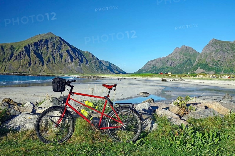 A bicycle on the beach with a view of the surrounding mountains and the sea, Flakstad, Lofoten, Nordland, Norway, Europe