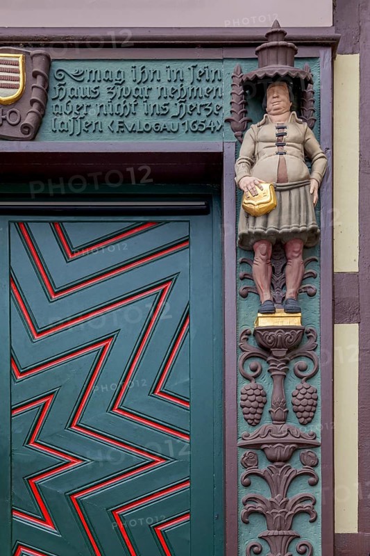 Detailed wooden door of a half-timbered house with statue and decorated façade, clear zigzag pattern, lettering and coat of arms, Wernigerode, Harz, Saxony-Anhalt, Germany, Europe
