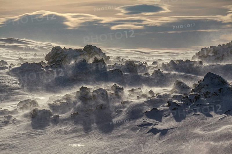 Solidified lava and stones in a snowstorm, windy, sunny, backlight, Myvatn, Iceland, Europe