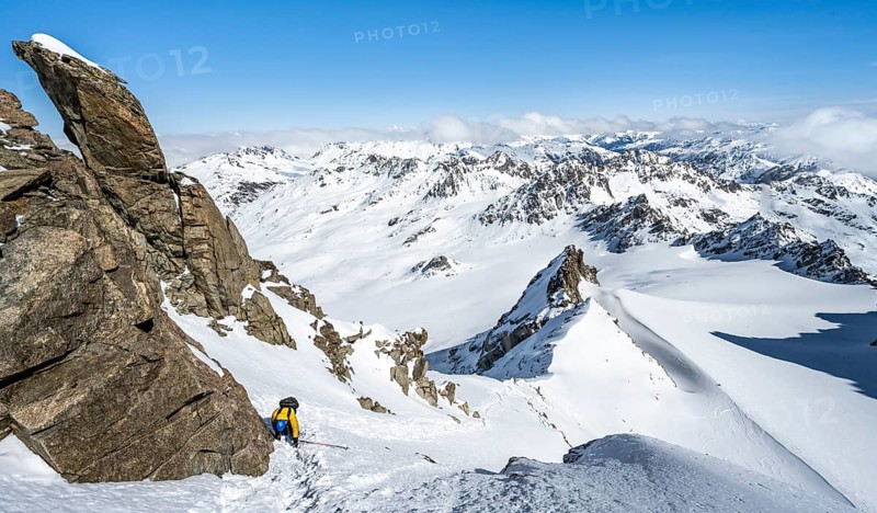 Mountaineer with ice axe and crampons, ascent through steep snowfield to Piz Kesch or Piz d'Es-cha in winter, view of mountain panorama with Vadret da Porchabella glacier, Albula Alps, Rhaetian Alps, Grisons, Eastern Switzerland, Switzerland, Europe