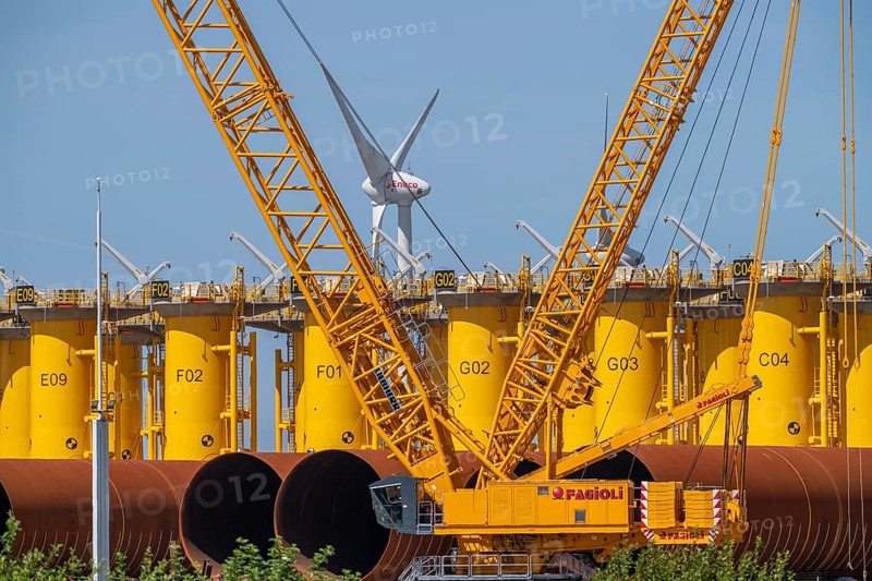 Transhipment centre for offshore wind turbines, which are transported here by the manufacturer and then shipped by special ships to the construction sites of the wind farms in the North Sea, here, yellow, so-called Transition Pieces Jackets, which are mounted on the monopile foundations driven into the seabed, on which the actual wind turbine is then mounted, in the port area of Vlissingen-Oost, Netherlands