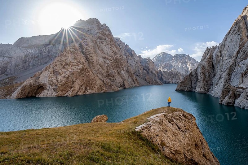Tourist at the blue mountain lake between rocky steep mountain peaks, Sun Star, Kol Suu Lake, Sary Beles Mountains, Naryn Province, Kyrgyzstan, Asia