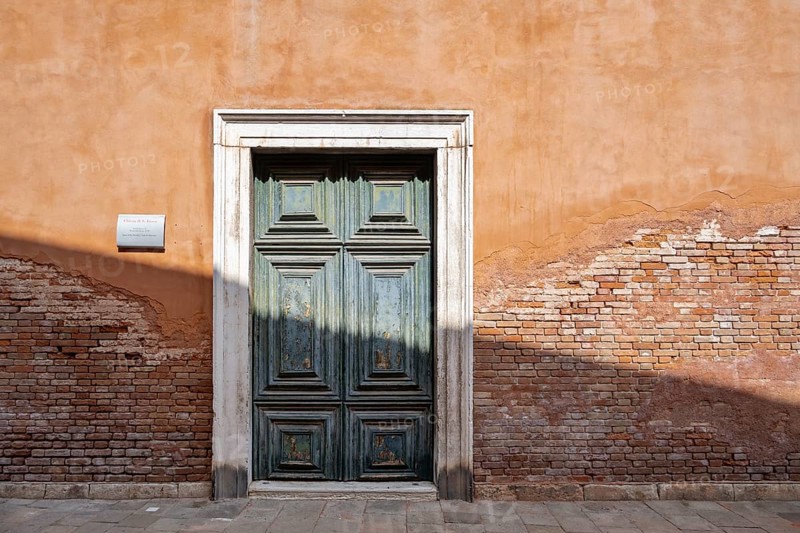 Red house facade with large green door, peeling plaster on brick wall, Venice, Veneto, Italy, Europe