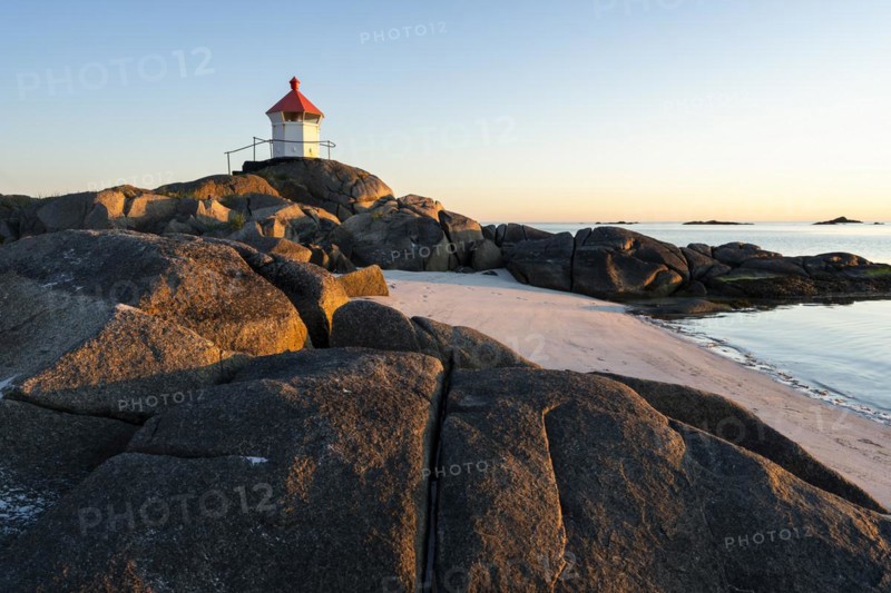 Seascape on the Lofoten Islands. The small lighthouse on the sandy beach of Eggum. Sea and rocks. At night at the time of the midnight sun in good weather, blue sky. Golden hour. Early summer. Eggum, Vestvagoya, Lofoten, Norway, Europe