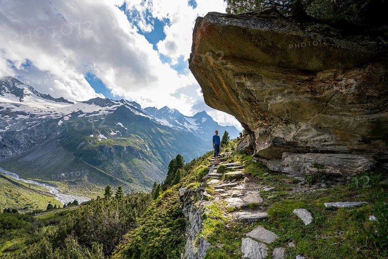 Mountaineer barefoot on a hiking trail under a rocky outcrop, mountain landscape with Waxeggkees, Berliner Höhenweg, Zillertal Alps, Zillertal, Tyrol, Austria, Europe