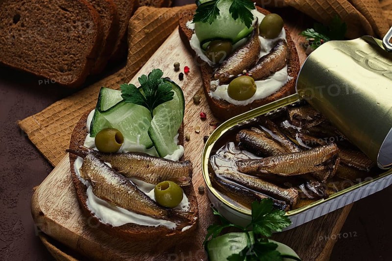 Sandwiches, black bread with sprats, cream cheese, cucumbers, on a cutting board, top view, close-up, no people