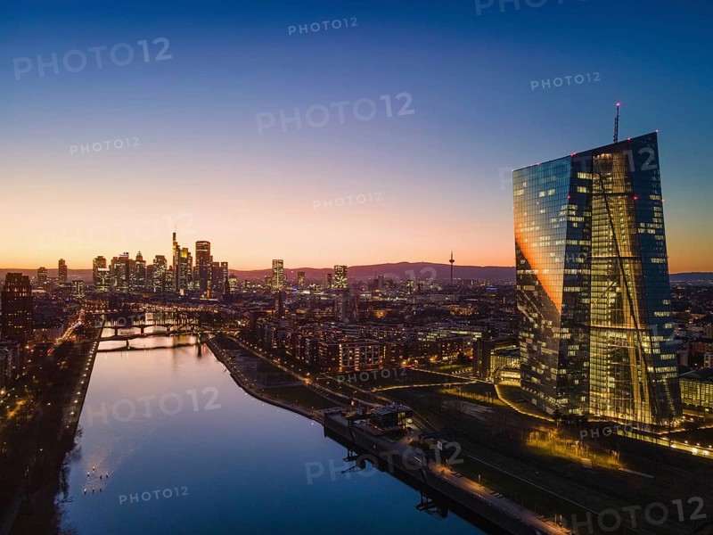 The lights in the offices of the European Central Bank (ECB) and the Frankfurt skyline glow in the evening after sunset. (Aerial view with a drone), Osthafen, Frankfurt am Main, Hesse, Germany, Europe