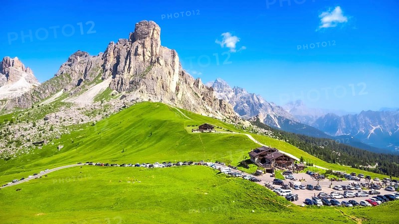 Panoramic view capturing the mountain shelter and parking area at passo giau in the italian dolomites on a sunny summer day