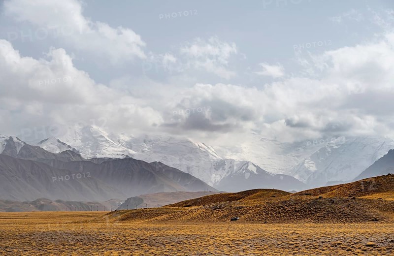 Glaciated, cloud-covered mountain peaks and golden meadows, Lenin Peak, Trans Alay Mountains, Pamir Mountains, Osh Province, Kyrgyzstan, Asia
