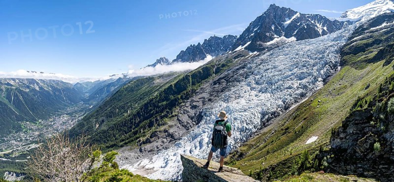 Mountaineer standing on a rock, mountain landscape with glacier Glacier des Bossons and summit of Aiguille du Midi, Chamonix, Haute-Savoie, France, Europe