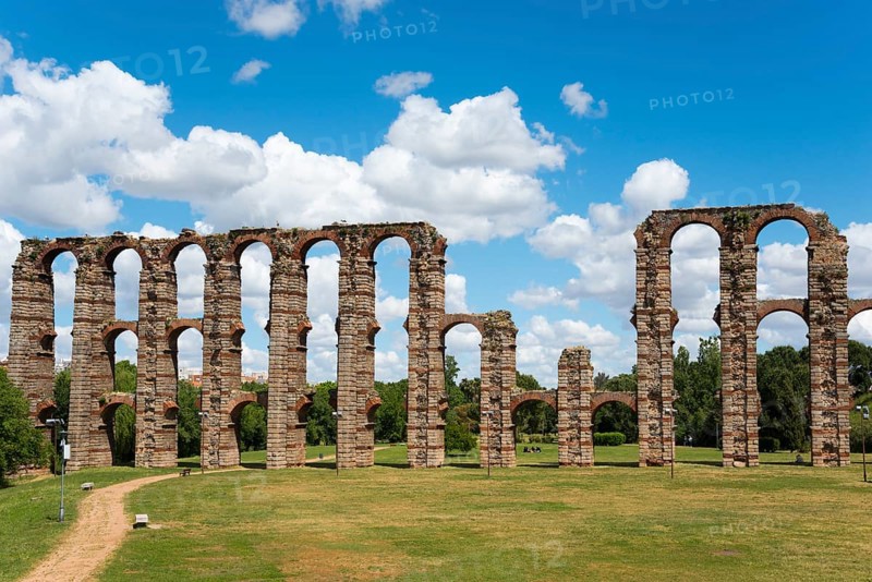 Antike Aquädukt-Ruinen mit hohen Bögen vor einem klaren Himmel und einer weitläufigen Grünfläche, Acueducto de los Milagros, Mérida, Merida, Badajoz, Extremadura, Spanien