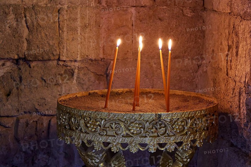 Several burning candles in an antique golden candlestick in front of a stone wall, creating a calm and warm atmosphere, Monastery of Our Lady of Mount Filerimos, Filerimos, hill not far from Rhodes Town, Ancient State of Ialyssos, Rhodes, Dodecanese, Greek Islands, Greece, Europe