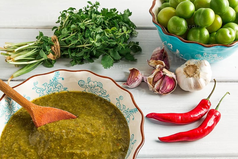 Tkemali sauce, traditional Georgian cuisine, green cherry plum, with ingredients for sauce, cilantro, mint, hot pepper, garlic, on a white wooden table, close-up, rustic, food background, no people, selective focus, sauce, green sauce, tkemali, georgian cuisine, homemade