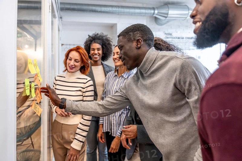 African man participating in a brainstorming process in a startup standing with colleagues at the coworking