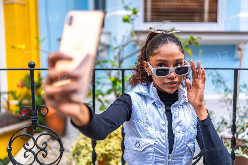 Beauty african american woman millennial in urban clothes taking selfie outside a colorful house