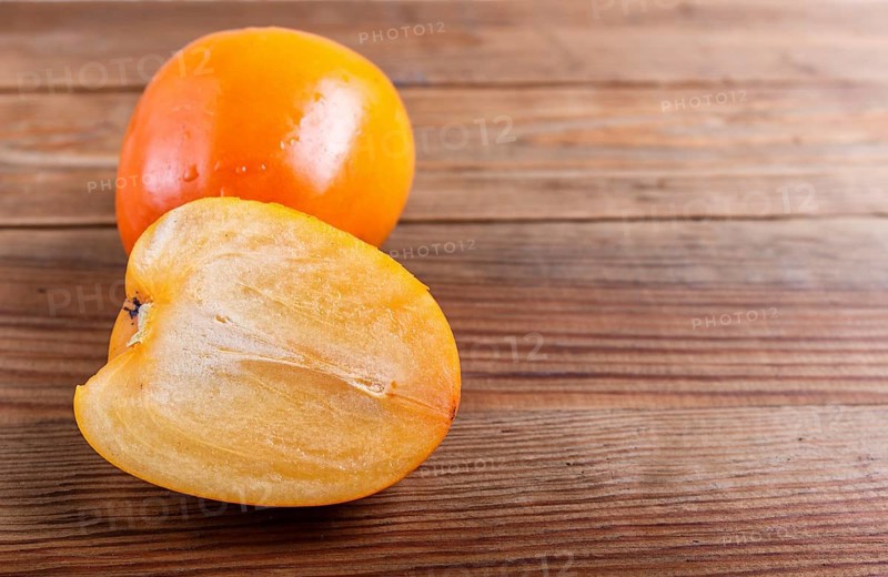Ripe orange persimmon on brown wooden background, with copy space