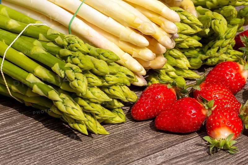 Green asparagus, white asparagus and fresh strawberries decorated on a rustic wooden table