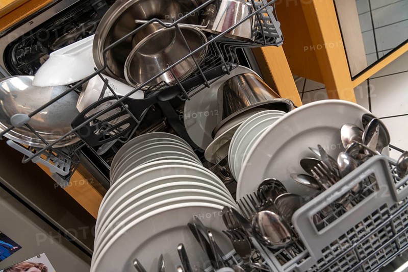 Dishwasher, full, with cleaned crockery, cutlery, cooking utensils