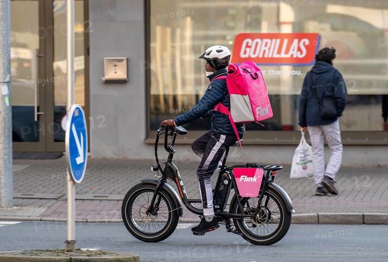 Bicycle courier of the fast delivery service Flink, delivers groceries, currently in over 40 German cities, within 10 minutes, orders via an app, works together with the REWE Group, in the background competitor Gorillas, Bochum, North Rhine-Westphalia, Germany, Europe