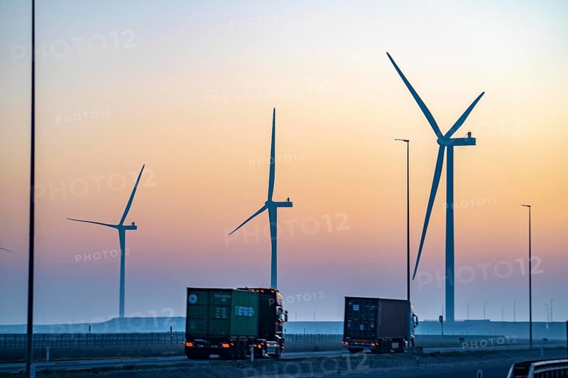Lorry on the road from Euromax Terminal Rotterdam, ENECO wind farm on the dike around the port of Maasvlakte 2, 22 wind turbines with a capacity of 116 megawatts, sunset, Rotterdam, Netherlands
