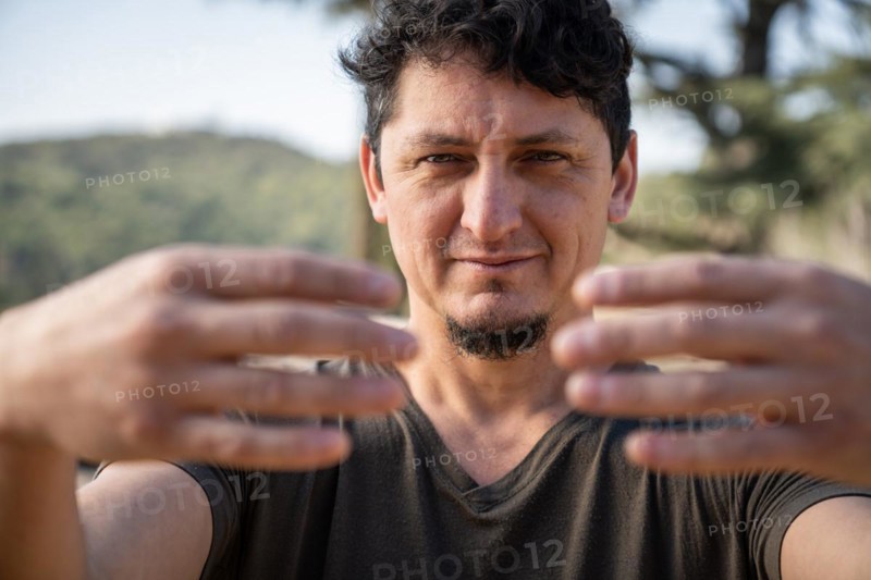 Close-up of a Caucasian adult man practicing the static posture of Tree Hugging, an essential technique in Chi Kung practice. Selective focus