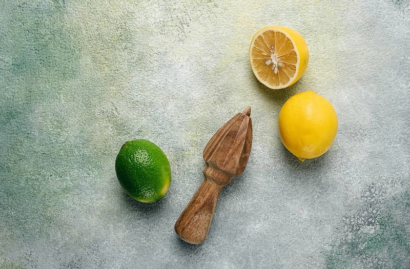 Wooden citrus reamer, manual lemon juicer, made of acacia wood, with citrus fruits on the table, top view