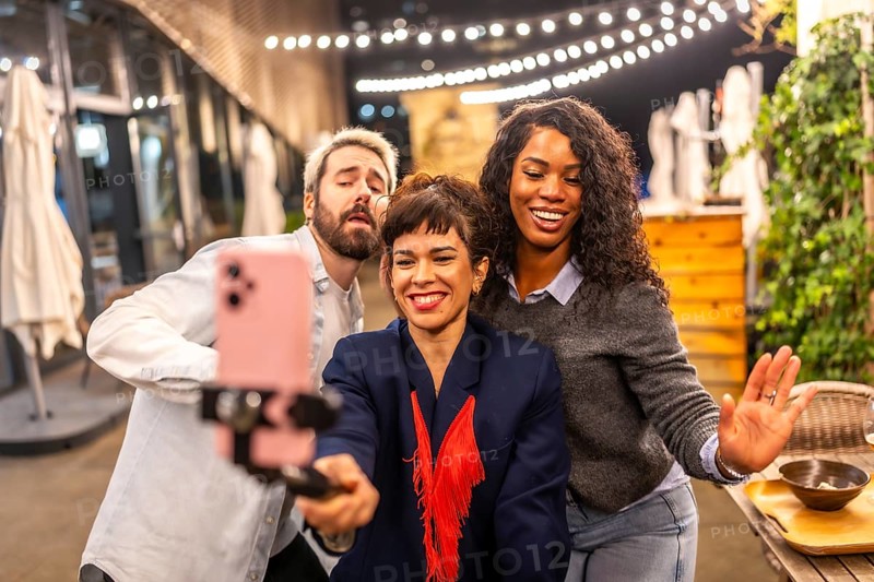Diverse friends dancing recording tik tok video with smartphone at night party
