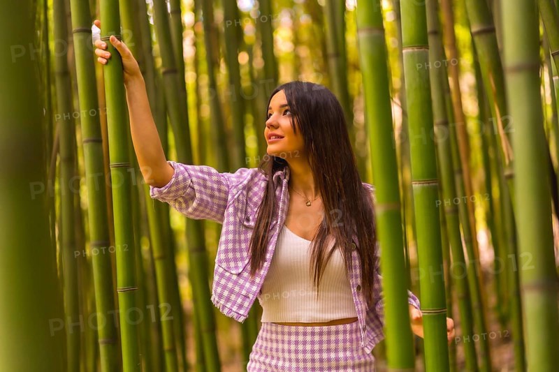 Young caucasian girl with a pink skirt in a bamboo forest. Enjoying summer holidays in a tropical climate, lifestyle of a girl walking and smiling in the forest