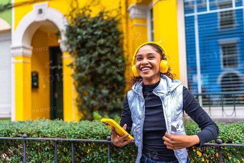 Happy african american woman smiling listening to music next to colorful houses