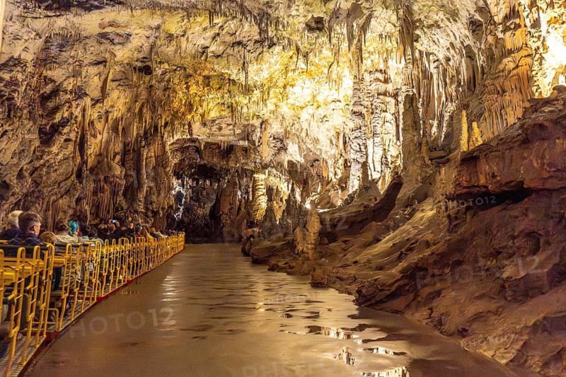 Tourists visiting the magnificent postojna cave in slovenia, riding an electric train through illuminated stalactites and stalagmites