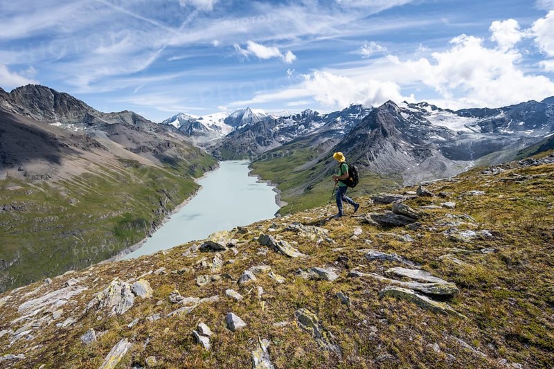 Mountaineer on the summit of Mont de la Blana, view of a blue mountain lake, Lac des Dix reservoir, behind mountain peak Mont Blanc de Cheilon with glacier, Hérménence, Valais Alps, Valais, Switzerland, Europe