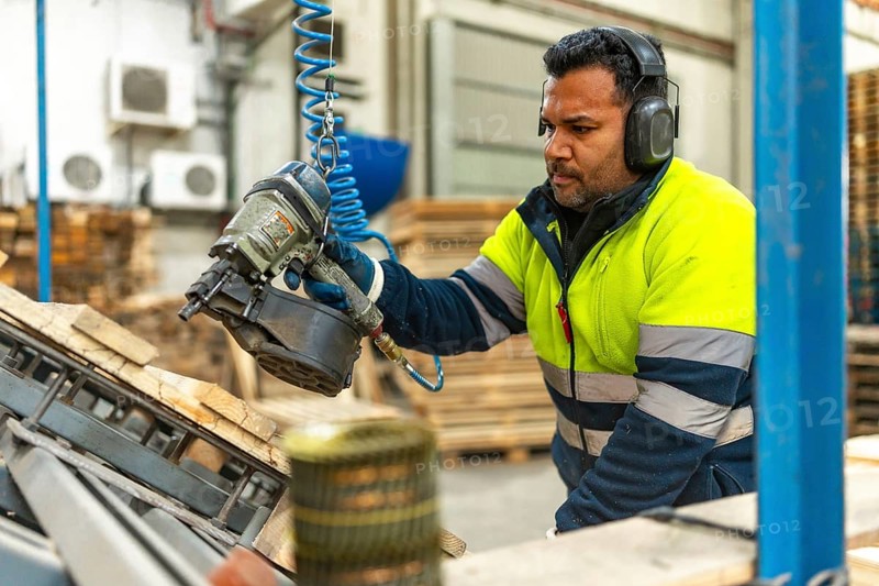 Man caucasian adult, worker in protective work gear recycling pallets in a factory of a recycling plant