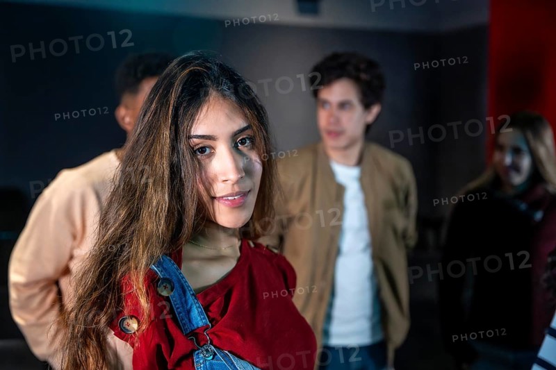 Group of young people enjoying a movie disco dance and event, with a smiling young woman in the foreground