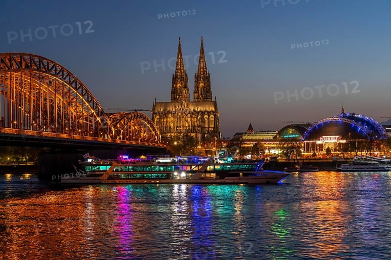 Cologne Cathedral, has been shining in new light since Easter 2025, the old metal halide lamps have been replaced by over 700 modern LED lamps, reducing energy consumption by around four-fifths, significantly improving the quality of light and greatly reducing light emissions, 12 KM of new cables were laid for this, KD Party Schiff, Hohenzollernbrücke, railway bridge over the Rhine, North Rhine-Westphalia, Germany, Europe