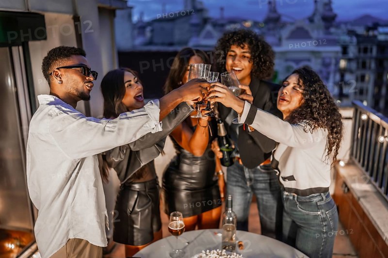 Top view of diverse and happy elegant multi-ethnic friends toasting with champagne during roof night party