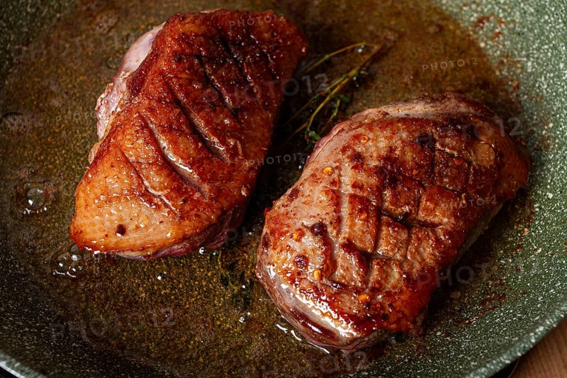 Cooking duck breast, in a frying pan, fried, with spices and herbs, close-up, no people