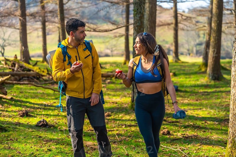 Hikers enjoying a healthy snack of apples while walking through a sunny forest during their outdoor adventure