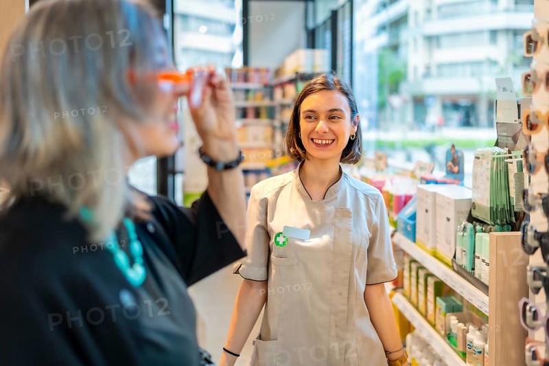 Young happy female ophthalmologist smiles and approves the glasses that a client is trying on