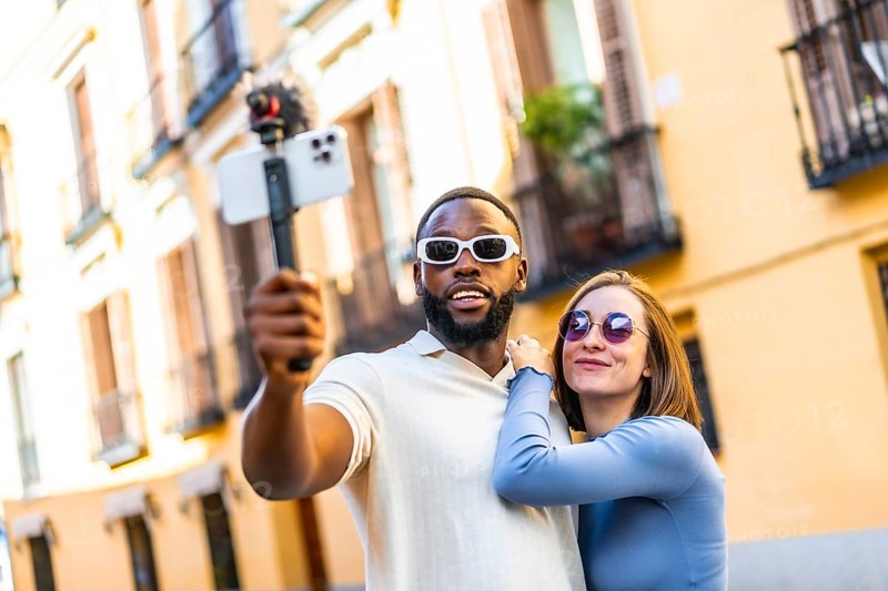 Multi-ethnic couple influencer vlogging from a travel destination standing in the city street