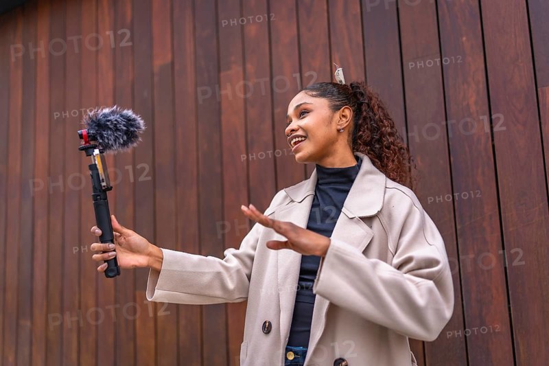 African american beauty woman vlogger talking to her audience streaming online next to wooden city wall
